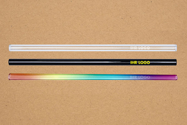Beispielansichten: 1 Glastrinkhalm in Klar mit Gravur, 1 Glastrinkhalm in Schwarz mit gelben Druck und 1 Glastrinkhalm in Regenbogen mit Gravur. Alle mit dem Schriftzug "Ihr Logo"