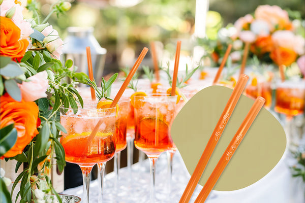 Glastrinkhalme für Hochzeiten – dekorative Drinks mit orangen Halmen auf festlicher Tafel, graviert mit ‚Mr. & Mrs.‘ für nachhaltige Hochzeitsideen 2025.