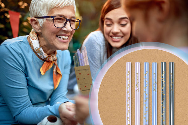 Mutter und Tochter haben sich herzlich im Arm. Im Vordergrund sind 6 in Gold bedruckte bunte Glastrinkhalme mit Herzen und Lieblingsmensch (2x Rosa, 2x Lavendel, 2x Grau): zum Bereich Gravur und Druck, Liebe und Freundschaft